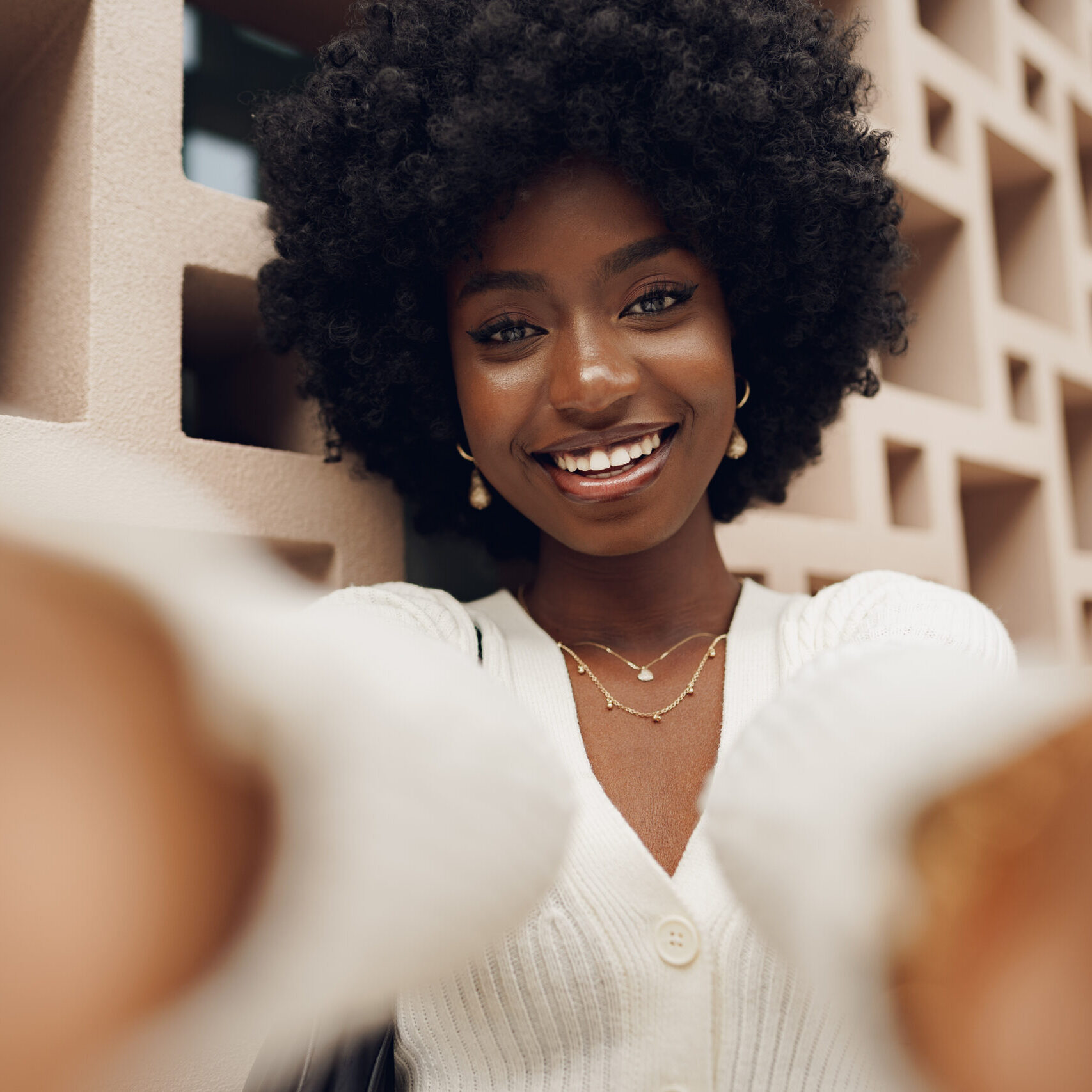 Stylish pretty young african woman with Afro hairstyle posing near geometric wall